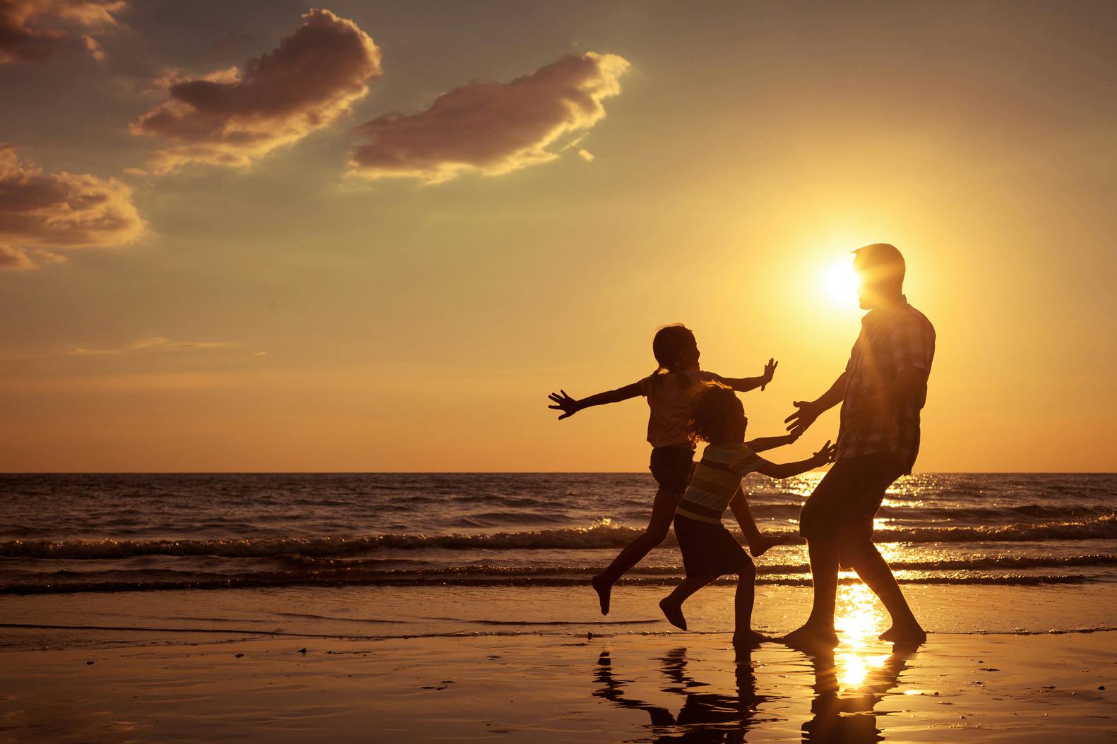 Family play on the beach at sunset